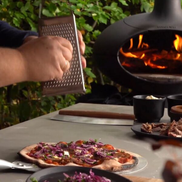 Morsø Forno Pizza Lovers Package - Garnishing a pizza cooked on the Forno - Lifestyle Image