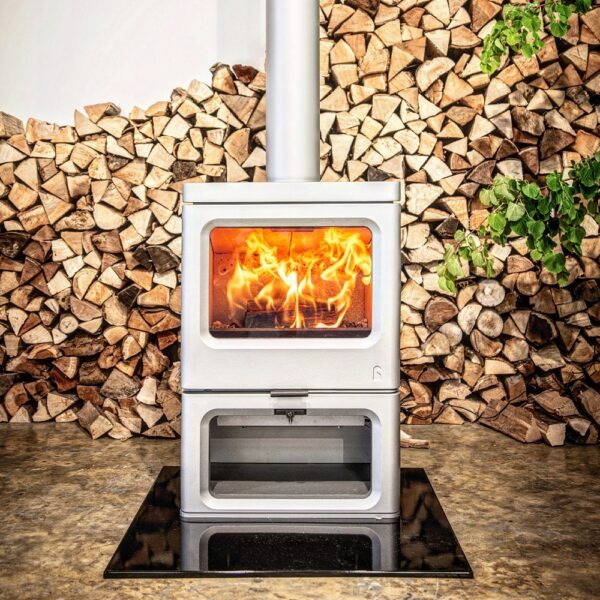 Charnwood Skye E700 on a Store Stand - Pewter Stove in front of log pile lifestyle image