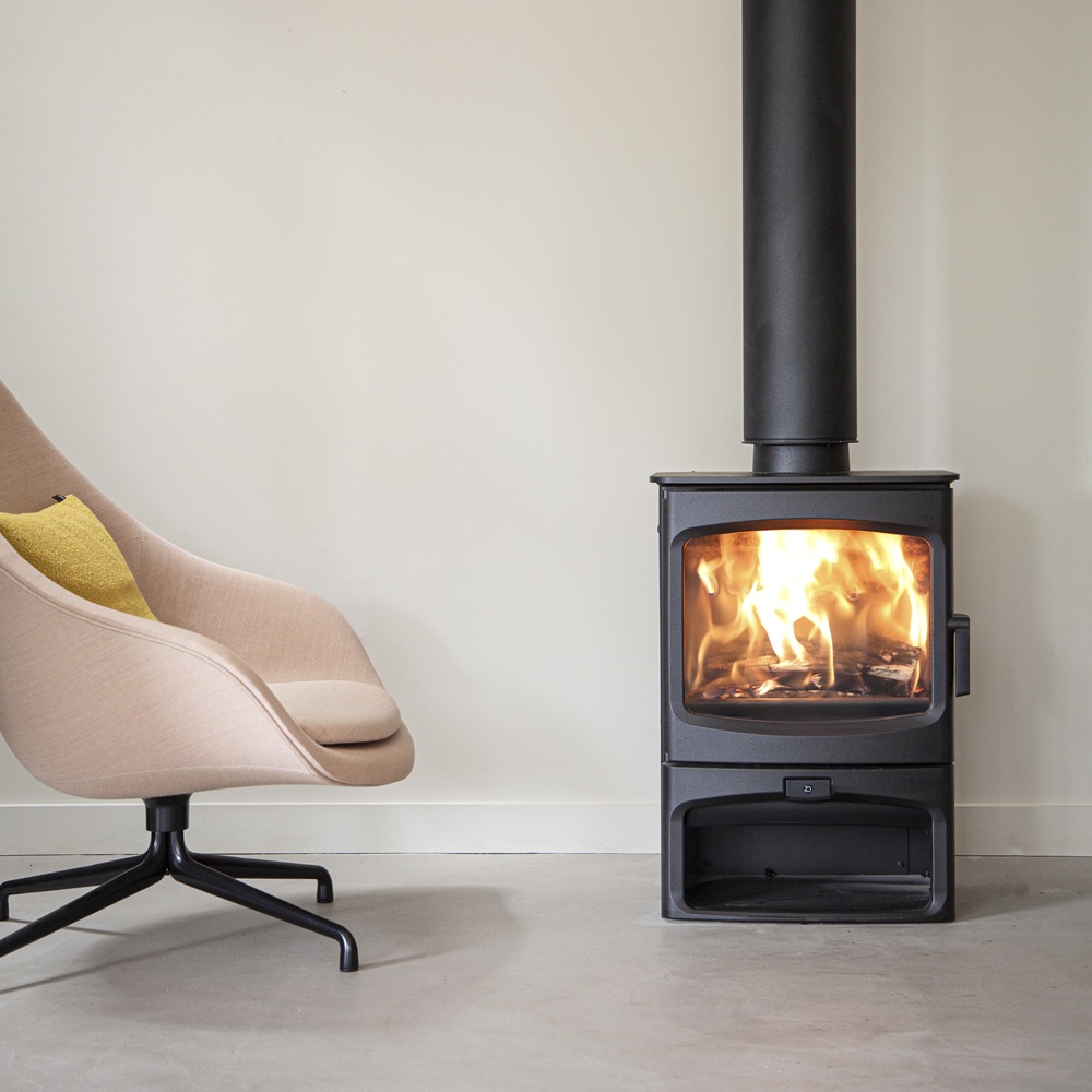 Charnwood Aire 700 Intelligent Stove in black next to a modern chair